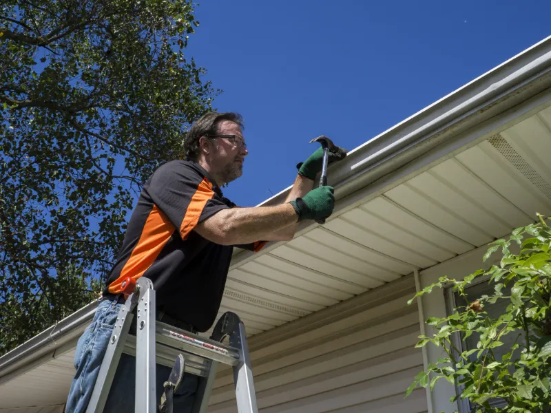 man repairing broken gutters