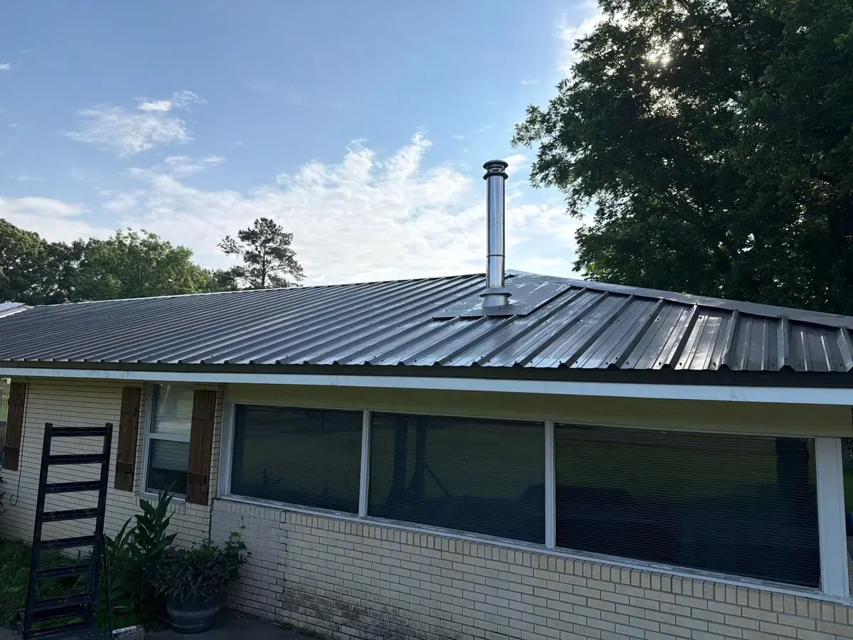 New dark 29-gauge metal roof with a flashed stainless flue pipe on a Central, LA brick home