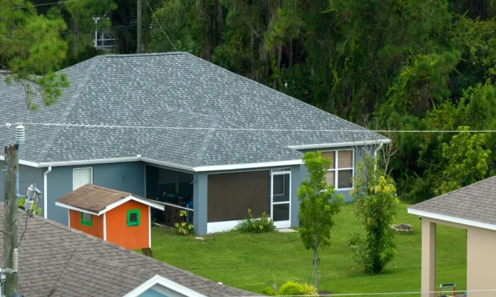 aerial view of house with gray roof and orange shed in backyard