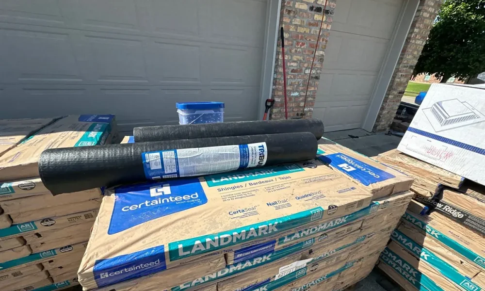 Pallets of CertainTeed Landmark AR shingles with rolls of TriBUILT synthetic underlayment staged in the driveway