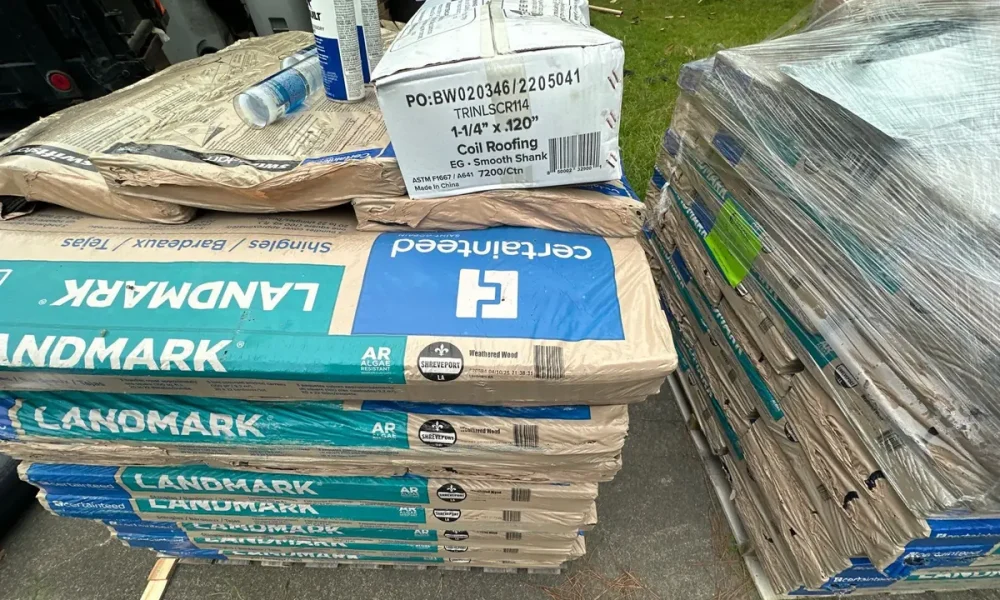 Pallet of CertainTeed Landmark shingles labeled Weathered Wood with a box of coil roofing nails on a Baker, LA job
