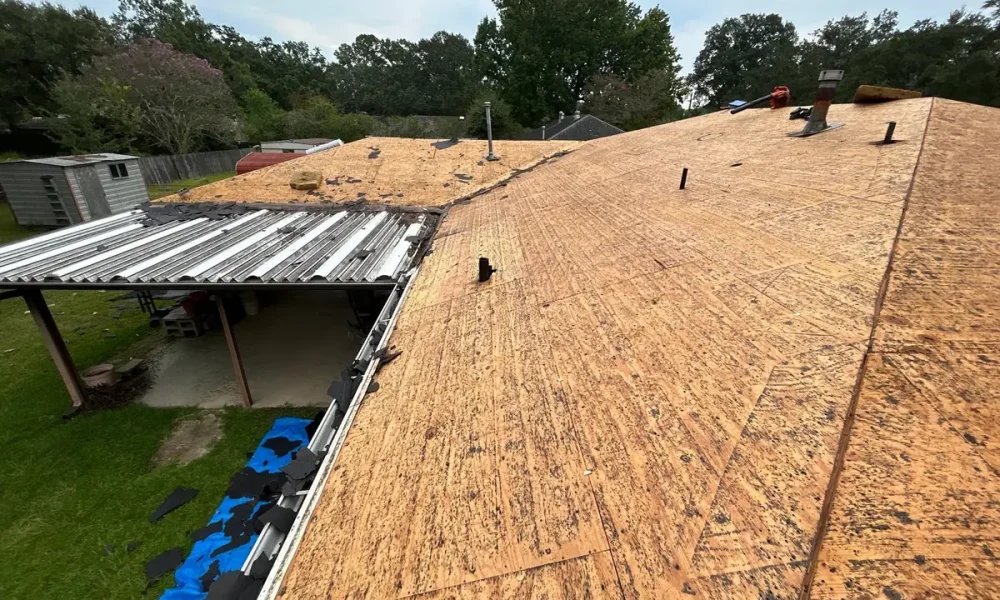 Bare roof decking at a valley beside a metal patio cover during a Baker, LA tear-off