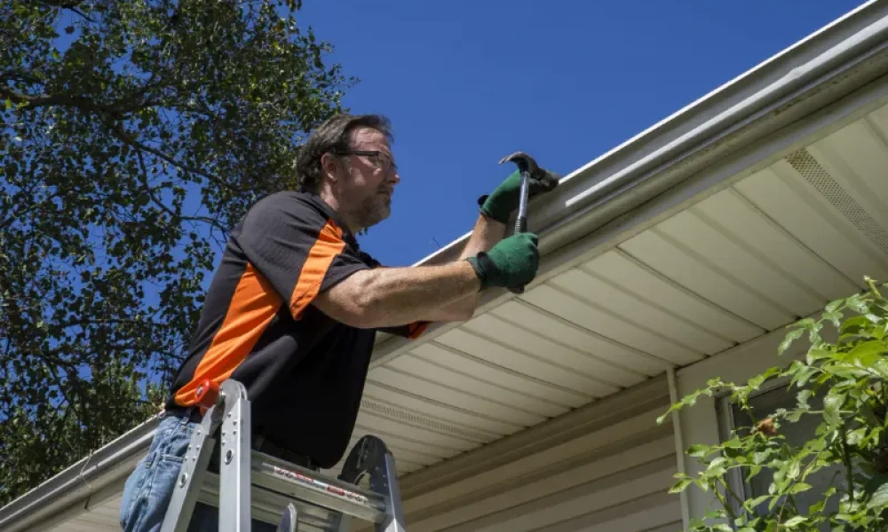 man repairing broken gutters