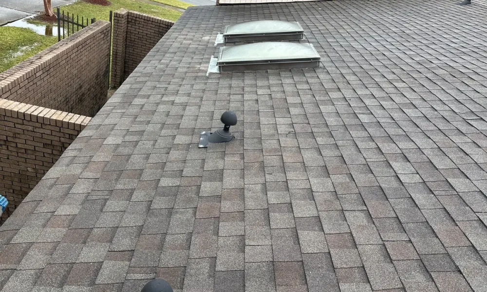 Low-slope roof section with two skylights and pipe vents on a Baker, LA home before the repair