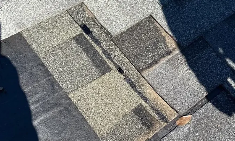 Shingles pulled back to the underlayment around a damaged area during a roof repair in Greenwell Springs, LA