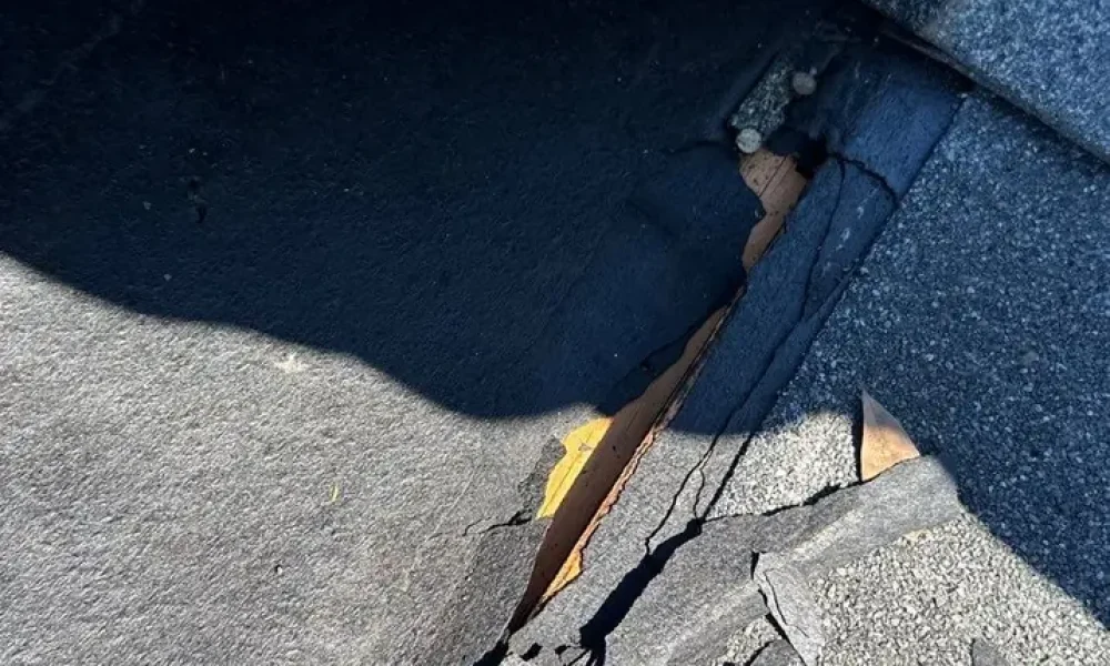 Cracked shingle pieces under a lifted top course during a Roof Rescue roof repair in Greenwell Springs, LA