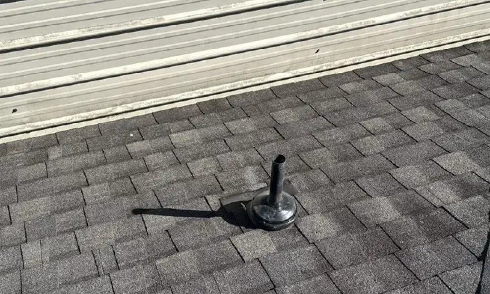 Pipe boot where the shingle roof meets a metal-paneled wall on a Greenwell Springs, LA home