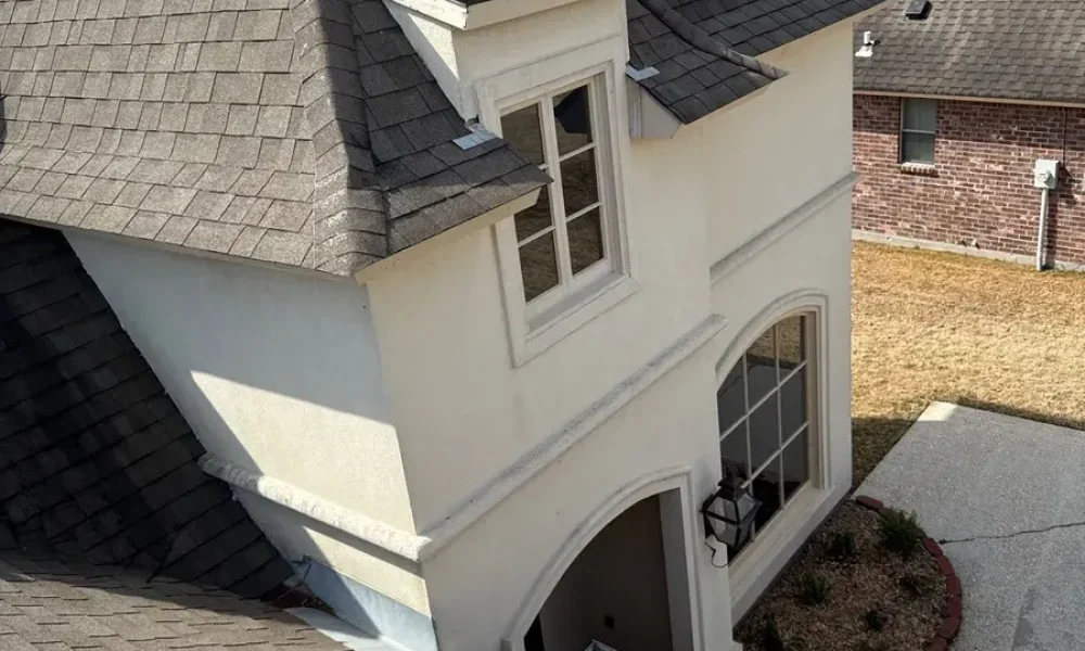 Weathered brown shingles around the front tower and dormer of a Saint Gabriel, Louisiana brick and stucco home before the roof replacement