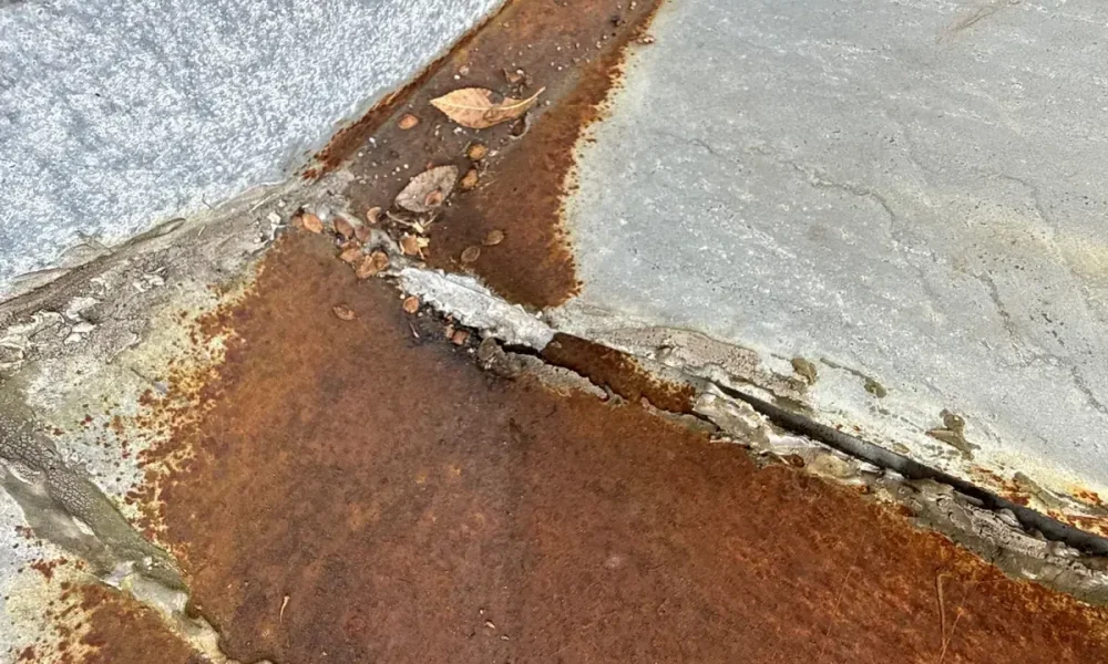 Rusted metal flashing where the old roof met the stucco wall, documented before the replacement