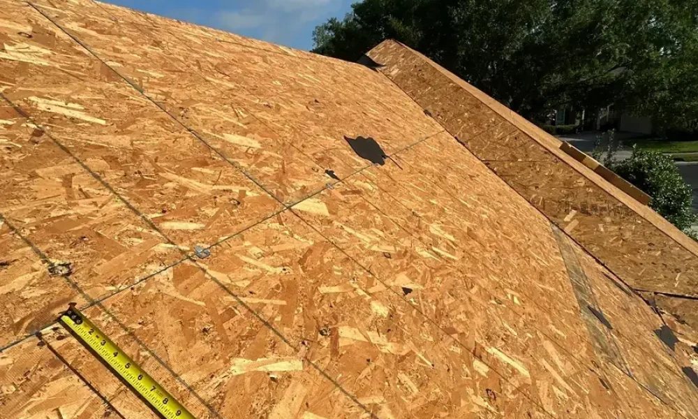 Crew member measuring the bare roof deck after tear-off on the Saint Gabriel home