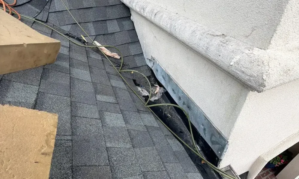 New architectural shingles laid up to new metal flashing along the stucco wall