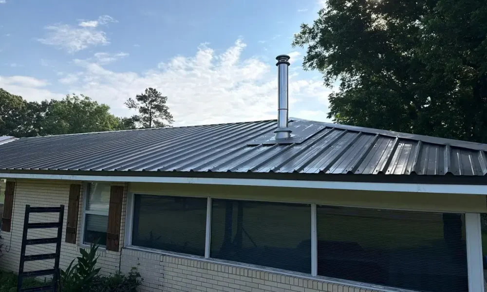 New dark 29-gauge metal roof with a flashed stainless flue pipe on a Central, LA brick home