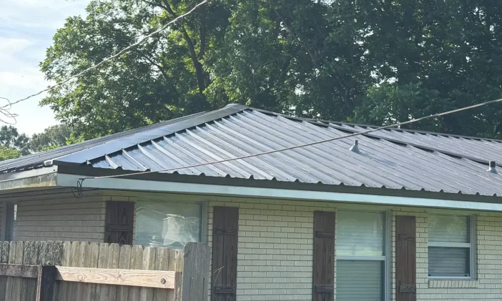 Hip corner of the new dark metal roof on a cream brick home in Central, LA